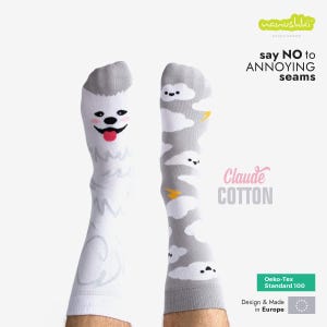 Op de afbeelding: Een paar sokken met een wit honden- en grijs wolkenontwerp. De sokken zijn gemaakt van Claude Cotton en zijn Oeko-Tex Standard 100 gecertificeerd. De tekst op de sokken luidt "say NO to ANNOYING seams".