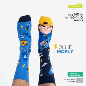 Pode incluir: Um par de meias azuis e azul marinho com um desenho de personagem de desenho animado. As meias apresentam um personagem com um chapéu amarelo e uma camisa azul, segurando um skate. As meias dizem "Ollie McFly" e "say NO to ANNOYING seams".