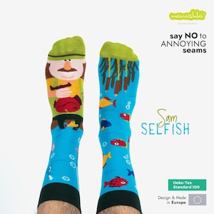Pode incluir: Um par de meias azuis com um pescador de desenho animado verde, amarelo e vermelho em uma meia e um padrão de peixes e algas marinhas na outra. As meias dizem "Sam Selfish" e "say NO to ANNOYING seams".
