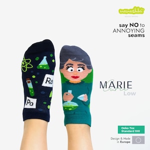 Peut inclure: Une paire de chaussettes basses sur le thème de la science. Une chaussette est bleu marine avec des symboles scientifiques verts et les lettres "Ra" et "Po". L'autre chaussette représente Marie Curie. Les chaussettes sont étiquetées "MARIE Curie Low."