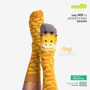 Könnte beinhalten: Ein Paar gelbe und braune Socken mit Giraffenmuster. Die Socken tragen den Text "Gigi Giraffe" und "say NO to ANNOYING seams". Die Socken werden in Europa hergestellt und sind nach Oeko-Tex Standard 100 zertifiziert.