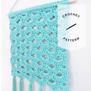 Może przedstawiać: Turkusowy wiszący dywanik wykonany na szydełku z wzorem rombów i frędzlami. Dywanik jest oznaczony jako "Crochet Pattern".