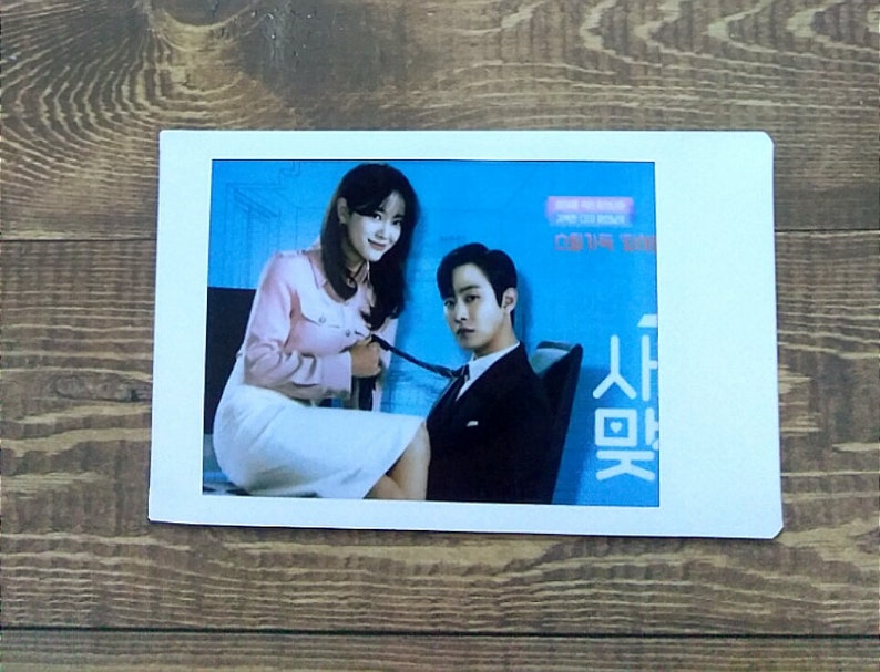 Pode incluir: Uma foto de um homem e uma mulher em uma cena do drama coreano "Love (ft. Marriage and Divorce)". O homem est&aacute; vestindo um terno preto e a mulher est&aacute; vestindo uma camisa rosa e uma saia branca. O texto "사랑은" &eacute; vis&iacute;vel na imagem.