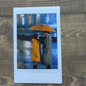 Pode incluir: Um casal est&aacute; debaixo de um guarda-chuva amarelo na chuva. A mulher est&aacute; usando um casaco amarelo e o homem est&aacute; usando um casaco cinza. O texto "시맨틱" &eacute; vis&iacute;vel no canto inferior esquerdo da imagem.