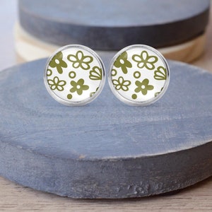 以下が含まれることがあります： 白い背景に緑色の花柄が描かれた、銀製のスタッドピアスのペアです。
