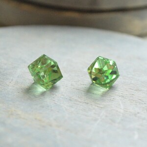 May include: Two green crystal earrings with a faceted design.