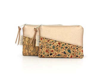 May include: Two rectangular zipper pouches featuring a metallic gold upper section and a lower section made of cork. One pouch has a natural cork texture, while the other displays a multi-colored terrazzo pattern. Each has a small tag labeled miyas.