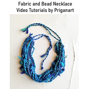 Op de afbeelding: Een handgemaakte stof- en kralenketting in blauwe en teal tinten. De ketting is gemaakt van gevlochten stoffen strengen en heeft kralen accenten. De tekst "Fabric and Bead Necklace Video Tutorials by Priganart" staat bovenaan.