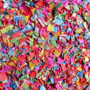 May include: A close-up of a pile of colourful fabric scraps. The scraps are in various shapes and sizes, and they are all made of different materials. The colours are bright and vibrant, and the scraps are arranged in a random pattern.