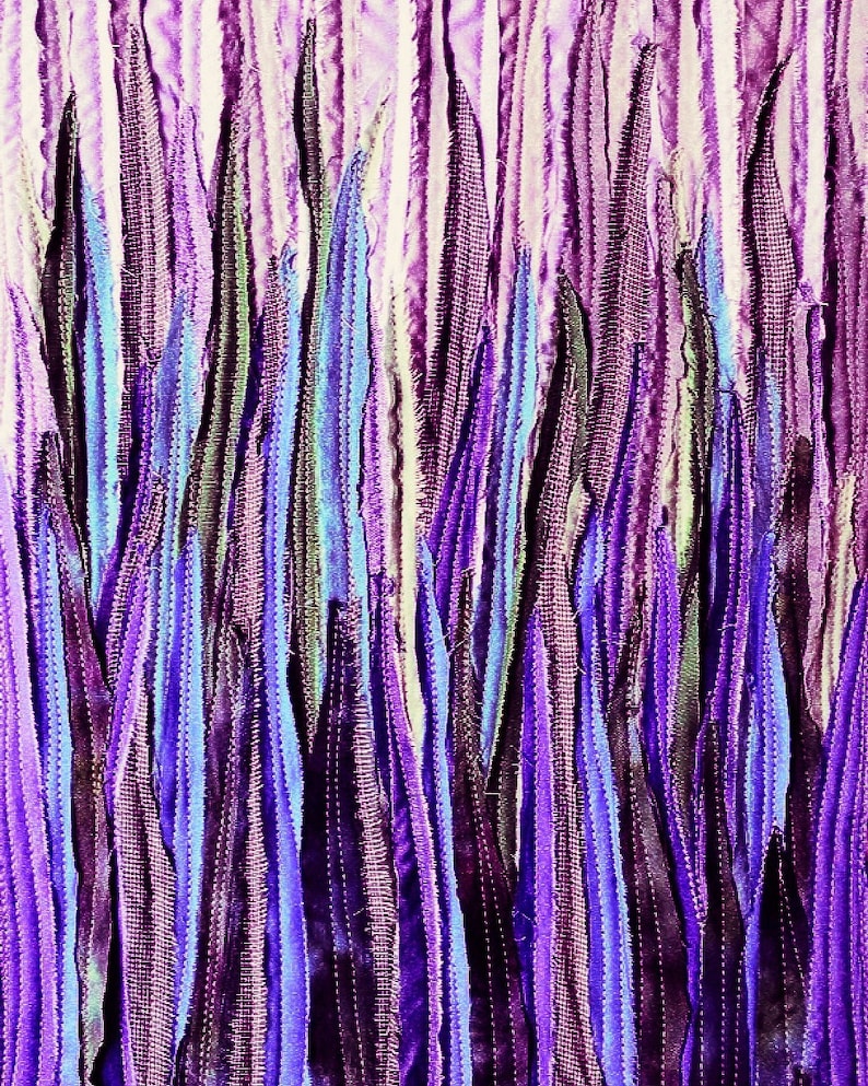 May include: A close-up of a fabric art piece with vertical strips of purple, blue, and white fabric. The fabric is sewn together to create a textured, abstract design.