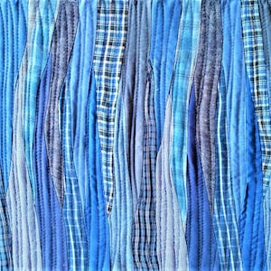 Puede incluir: Una colcha hecha de tiras de tela azul y blanca cosidas juntas en un patr&oacute;n ondulado. La tela es una mezcla de azul s&oacute;lido y cuadros.