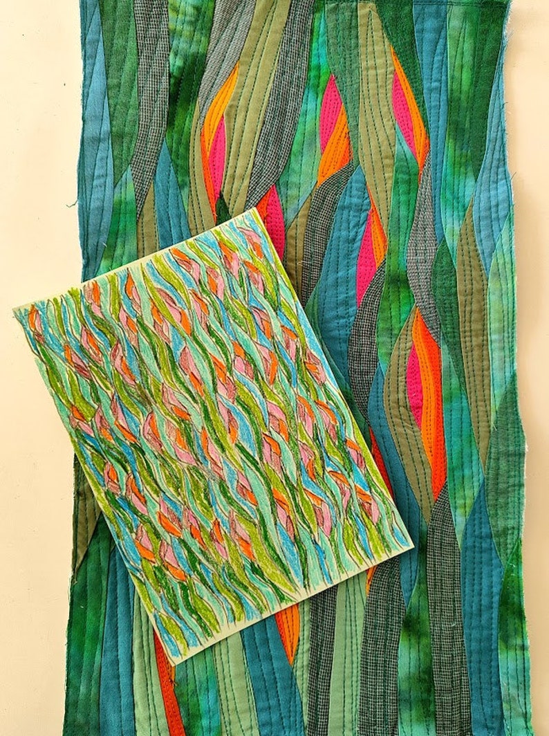 May include: A close-up of a hand-stitched fabric art piece with a green, blue, orange, and pink colour scheme. The fabric is arranged in a wavy pattern, resembling leaves or water. A smaller drawing of a similar design is placed on top of the fabric.