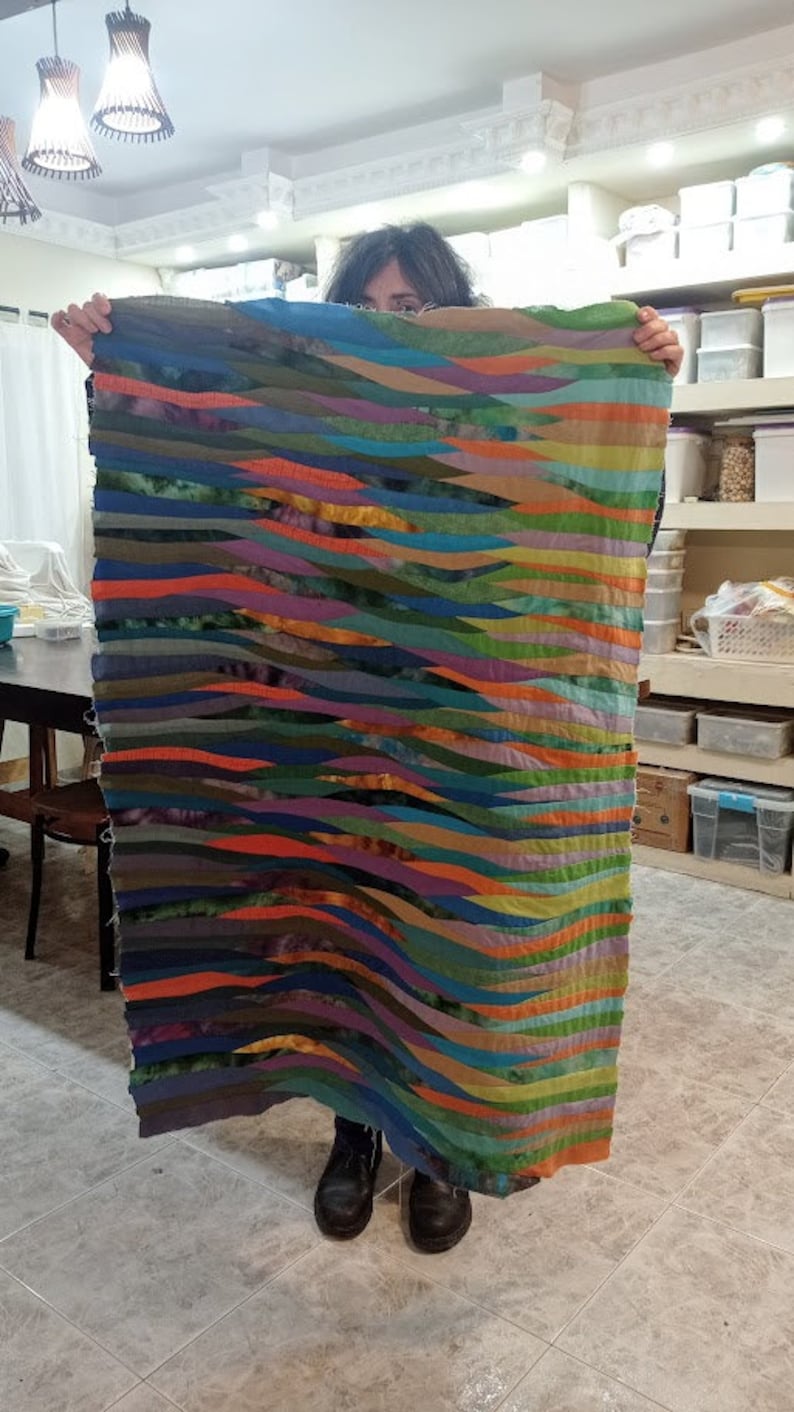 May include: A colorful woven wall hanging with a wavy pattern in shades of blue, green, orange, and purple.