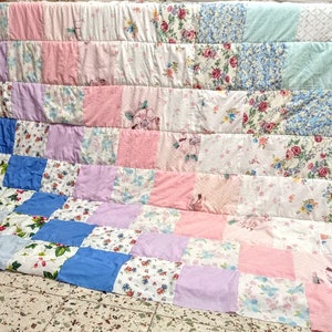 May include: A patchwork quilt made from various floral patterned fabrics in shades of pink, blue, and white.
