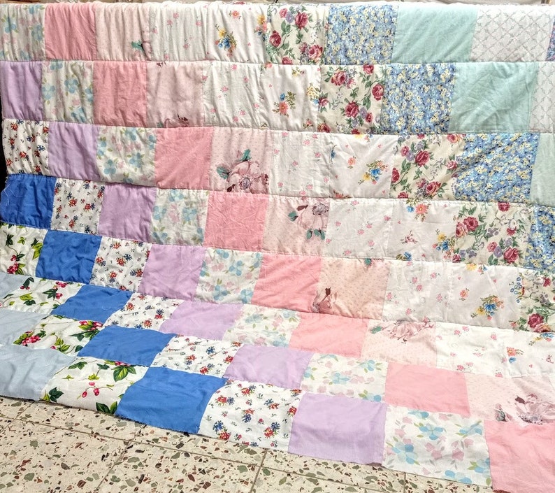 May include: A patchwork quilt made from various floral patterned fabrics in shades of pink, blue, and white.