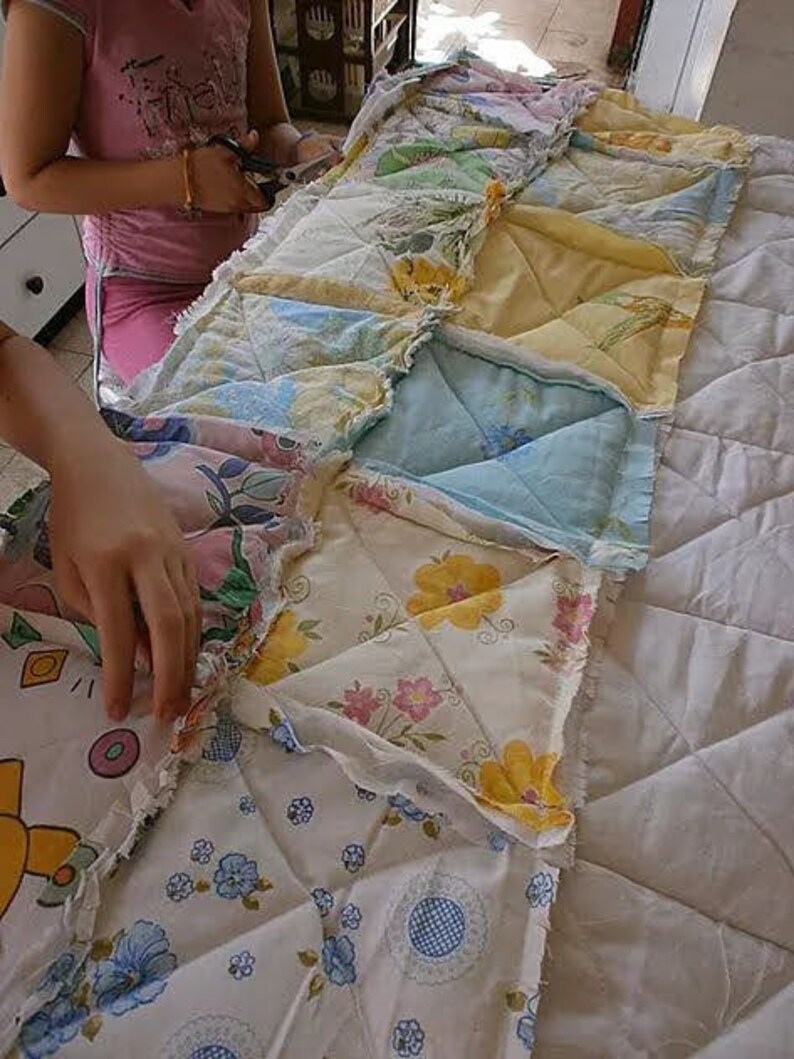 May include: A patchwork quilt being sewn together with different floral patterns in shades of blue, yellow, pink, and white.