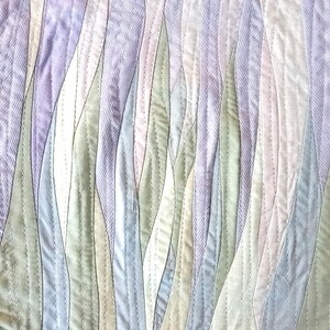 May include: A quilted fabric wall hanging with a wavy pattern in shades of purple, green, and blue.