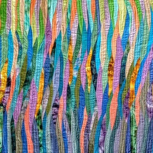 May include: A colorful abstract quilt with a pattern of vertical, wavy lines in shades of blue, green, purple, orange, and yellow.