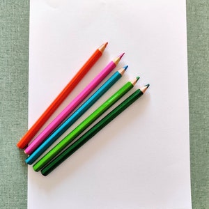 May include: A white sheet of paper with five coloured pencils on top. The pencils are orange, pink, blue, green, and dark green.