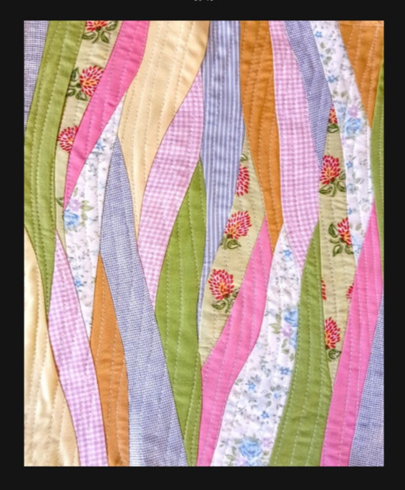 May include: A patchwork quilt with a wavy design featuring various floral patterns in shades of pink, green, yellow, and blue.