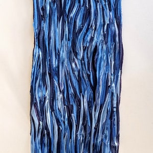 Puede incluir: Un tapiz de pared hecho de tiras de tela azul cosidas juntas. La tela es de varios tonos de azul, de claro a oscuro.