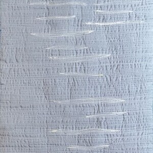 May include: A close-up of a light blue textured fabric with a subtle white pattern. The fabric has a woven appearance and a soft, smooth feel.