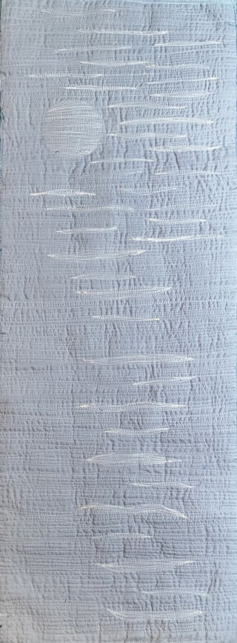 May include: A close-up of a light blue textured fabric with a subtle white pattern. The fabric has a woven appearance and a soft, smooth feel.