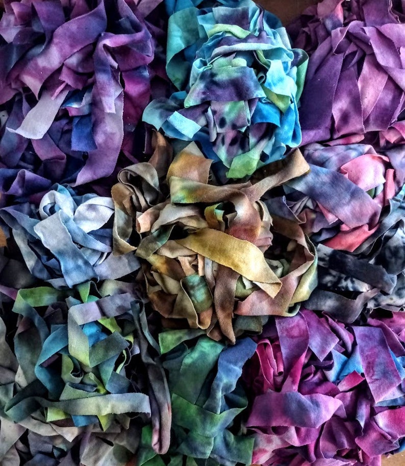 Puede incluir: Una colecci&oacute;n de recortes de tela coloridos en tonos azules, morados y verdes. La tela est&aacute; atada y retorcida en una variedad de formas y texturas.