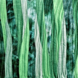 Peut inclure: Un gros plan sur une courtepointe en tissu avec un motif ondul&eacute; vertical dans des tons de vert. Le tissu est cousu en bandes, cr&eacute;ant un aspect textur&eacute;.