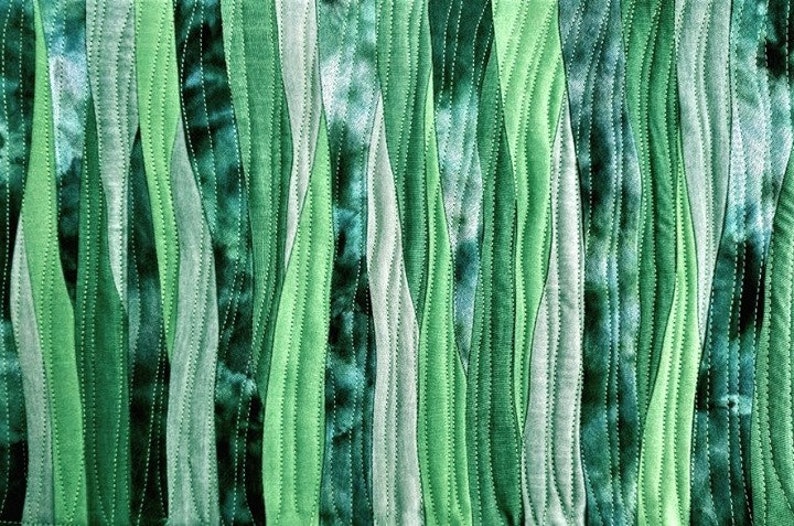 Peut inclure: Un gros plan sur une courtepointe en tissu avec un motif ondul&eacute; vertical dans des tons de vert. Le tissu est cousu en bandes, cr&eacute;ant un aspect textur&eacute;.