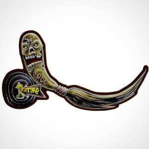 May include: A brown leather patch with a skull and a horn. The horn is wrapped with a brown cord and has a long, brown, braided tail. The patch has a black circle with a white number 1 and the word "TIRO" in yellow.