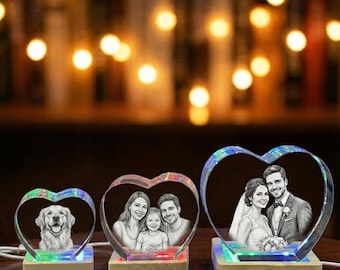 Puede incluir: Tres exhibidores de fotos de cristal en forma de corazón con luces LED. Los exhibidores presentan imágenes grabadas de un perro, una familia y una pareja de bodas. Cada uno se asienta sobre una base de madera, con luces de colores.