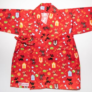 May include: Red baby kimono with a dog and bone print. The kimono has a tie closure and a small label that says "giko sakai".