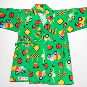 May include: Green kimono robe with a construction theme. The robe is covered in a repeating pattern of yellow construction signs, orange traffic cones, and blue trucks. The text "STOP" appears on several of the signs.