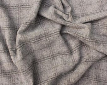 Può includere: Primo piano di un tessuto grigio con un motivo a quadri. Il tessuto è drappeggiato, mostrando pieghe e consistenza. Il motivo a quadri presenta sottili linee grigio scuro su uno sfondo grigio più chiaro. Il tessuto sembra essere un materiale di peso medio.