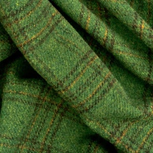 May include: Green fabric with a brown and gold plaid pattern. The fabric is woven and has a textured surface.