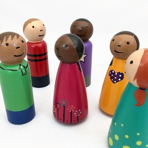 May include: A set of six wooden peg dolls with painted features and clothing. The figures include various skin tones, hair colors, and outfits, such as a green shirt with blue pants, a red shirt with black stripes, a pink dress with flowers, and a yellow dress with a heart.