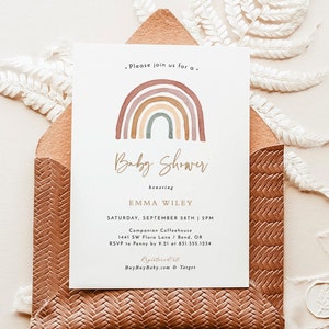 Op de afbeelding: Een baby shower uitnodiging met een aquarel regenboog ontwerp. De uitnodiging is voor Emma Wiley en is gepland voor zaterdag 28 september om 14:00 uur bij Companion Coffeehouse in Bend, Oregon. RSVP naar Penny voor 21 september op 831.555.1234. BuyBuy Baby.com & Target.