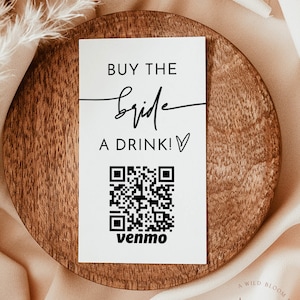 May include: White card with black text that reads "Buy the bride a drink!" with a black and white QR code and the word "Venmo" below it.