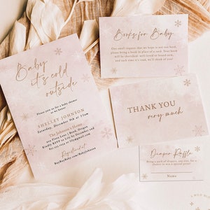 Op de afbeelding: Set briefpapier voor een babyshower met winterthema. De uitnodiging luidt "Baby it's cold outside" met sneeuwvlokaccenten. Bevat kaarten voor boeken, bedankjes en een luierloterij, allemaal in zachte roze tinten.