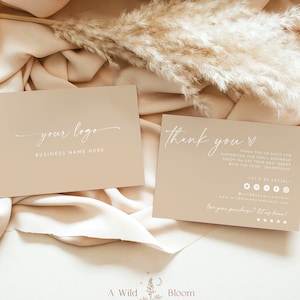 Könnte beinhalten: Zwei beigefarbene Dankeskarten mit weißem Text. Die obere Karte zeigt "your logo" und "BUSINESS NAME HERE". Die untere Karte zeigt "Thank you" mit einem Herzsymbol und "THANK YOU SO MUCH FOR SUPPORTING OUR SMALL BUSINESS! ENJOY 15% OFF YOUR NEXT ORDER WITH THE CODE THANKYOUIS". Die Karte enthält auch Social-Media-Symbole und den Text "LET'S BE SOCIAL!" und "www.wildbloomcreations.com". Am unteren Rand der Karte steht "for your purchase? let us know!" mit fünf Sternen. Die Karten liegen auf einem beigefarbenen Stoffhintergrund mit einem getrockneten Pampasgras-Zweig.
