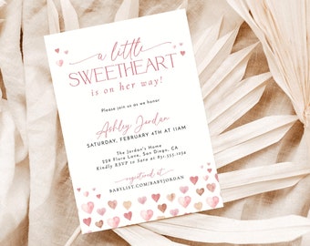 May include: A white invitation card with pink text and heart illustrations. The text reads "a little SWEETHEART is on her way!" and includes event details for Ashley Jordan's baby shower. The card is decorated with watercolor hearts.