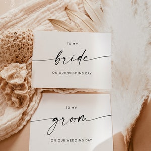 Op de afbeelding: Twee witte kaarten met zwarte tekst. De bovenste kaart zegt "Aan mijn bruid op onze trouwdag". De onderste kaart zegt "Aan mijn bruidegom op onze trouwdag".