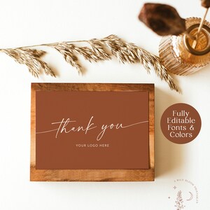May include: A brown wooden frame with a brown background and white text that says "thank you" and "your logo here". The frame is on a white surface with a vase of dried grass and a wooden stick.