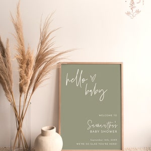 May include: A sage green printable sign with white text that reads "hello baby" and "Welcome to Samanthi's Baby Shower September 14th, 20XX We're so glad you're here!"