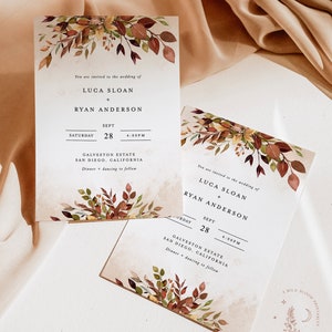 May include: Two wedding invitations with a watercolor design of fall leaves in shades of red, orange, and yellow. The invitations are printed on a textured paper with a beige background. The text on the invitations reads: "You are invited to the wedding of Luca Sloan + Ryan Anderson" and "Saturday, September 28, 4:00 PM, Galveston Estate, San Diego, California, Dinner + dancing to follow."