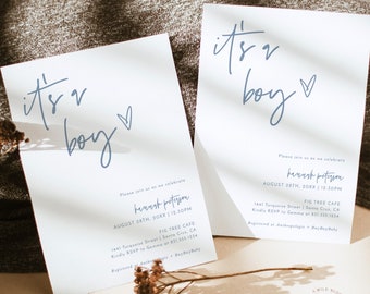 May include: Two white cards with blue calligraphy that reads "it's a boy" and a heart. The cards are baby shower invitations with the date, time, and location of the event. The text also includes the name of the parents-to-be, "Hanush Petyson", and the location of the event, "Fig Tree Cafe".