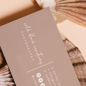 May include: A light brown business card with the text "wild bloom creations PHOTOGRAPHY" in white script font. The card also includes contact information, including a phone number, email address, website address, and social media icons.