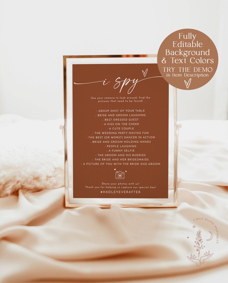 May include: A printable "I Spy" game card with a brown background and white text. The card lists items to find in wedding photos, such as "bride and groom laughing" and "a funny selfie". The card also includes the hashtag #HADLEYEVERAFTER.