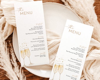 May include: Two white menus with gold lettering on a white plate. The menus list a selection of food items, including Caprese Salad, Assorted Dips, Assorted Baguettes, and Sweets. The menus are decorated with a watercolor illustration of champagne glasses.